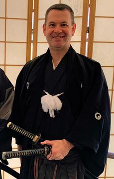 A martial arts instructor in black smiling